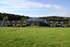 Flacher Bau des Schullandheims auf grüner Wiese