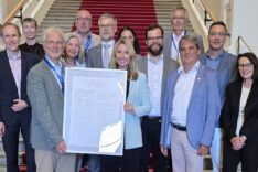 Die Vertreterinnen und Vertreter des Runden Tisch Klassenfahrten stehen mit Ministerin Stolz auf den Treppenstufen des Treppenhauses im Bayerischen Landtag. Die Ministerin und der Präsident der Jugendherbergen in Bayern - Herr Umbach - halten das gerahmt Memorandum.