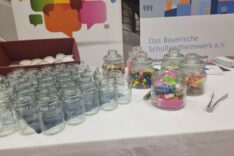 Auf dem Messetisch stehen Gläser gefüllt mit Süßigkeiten und leere Gläser. Besucher werden eingeladen, für schöne Erinnerungen an Schullandheimaufenthalte in die leeren gläser Süßes zu füllen.