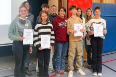 Jugendliche, die an dem MINT-Camp teilgenommen haben stehen in der Turnhalle des Schullandheims Hobbach und halten ihre Urkunden in die Kamera.